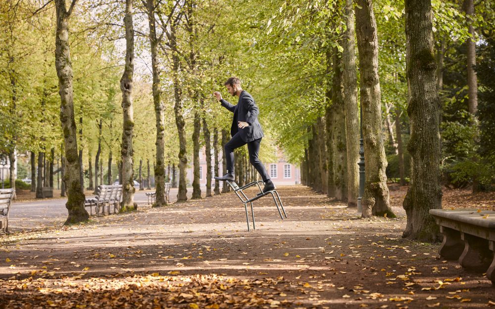 Mann balanciert auf einem Stuhl im Park in Düsseldorf