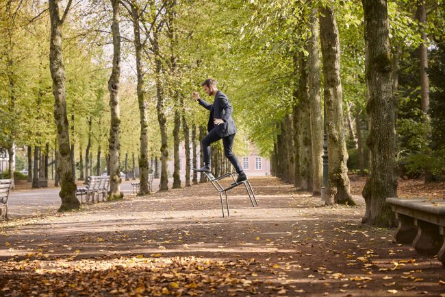 Mann balanciert auf einem Stuhl im Park in Düsseldorf