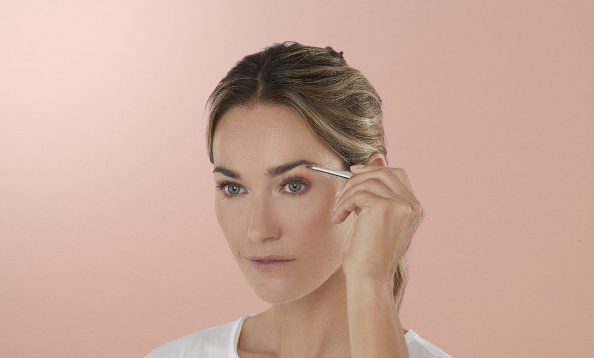 Frau zupft sich die Augenbraun