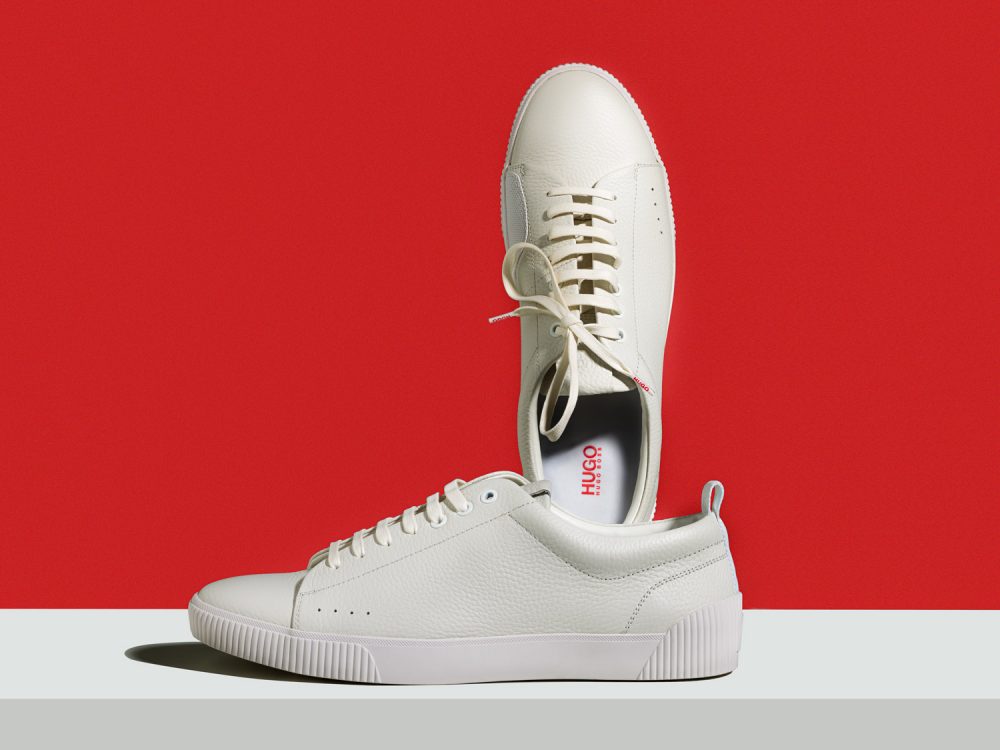 weißer Hugo Boss Schuhe vor roten Hintergrund. Produktfoto