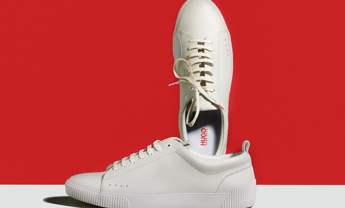 weißer Hugo Boss Schuhe vor roten Hintergrund. Produktfoto