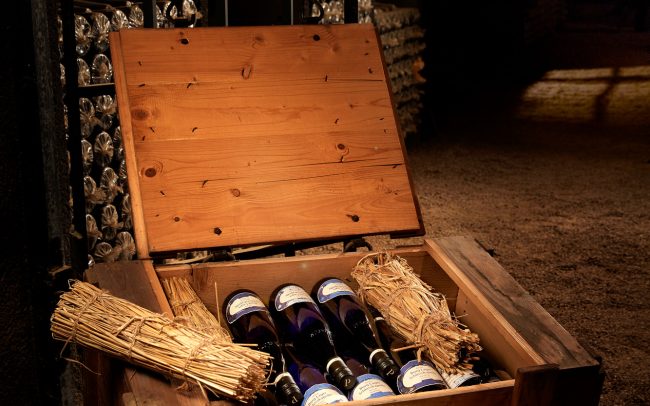 Pieroth Weinkeller mit einer alten Box mit Pieroth Weinflaschen gefüllt und Stroh-Hülsen als Deko